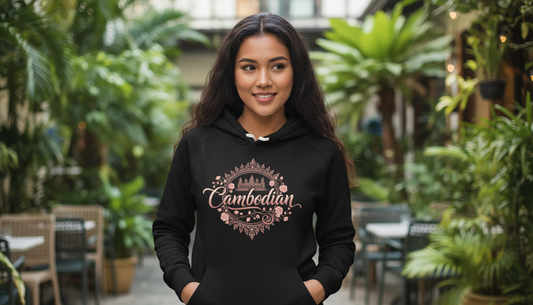 Woman wearing a black hoodie with 'Cambodian' design in an outdoor setting with greenery.