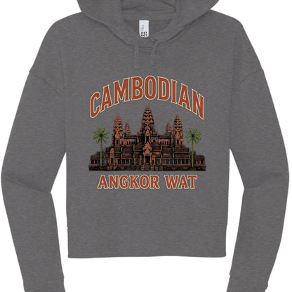 The artwork is a multi-colored illustration celebrating Cambodian heritage:

Typography: The word "CAMBODIAN" is arched at the top, and "ANGKOR WAT" is printed straight across the bottom. Both are in a bold, blocky font with a terracotta-orange fill and a light cream or tan outline.

The Temple: A central illustration of the Angkor Wat temple complex is rendered in earthy brown and reddish-orange tones, highlighting its iconic tiered spires.

Landscaping: Two vibrant green palm trees flank the temple, addin