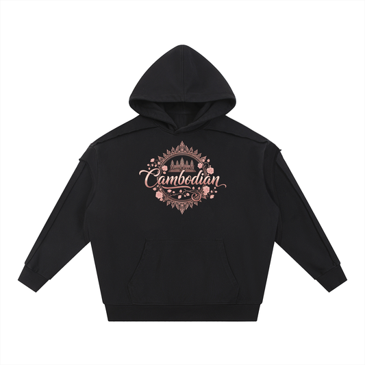 The graphic is rendered in a rose gold or metallic pink hue and incorporates several cultural and decorative elements:

Typography: The word "Cambodian" is written in a fluid, elegant script font across the center.

Iconography: Directly above the text is an illustration of Angkor Wat, the iconic temple complex from Cambodia.

Framing: The entire central design is enclosed within a circular frame of blooming roses and delicate vines.

Ornate Borders: The top and bottom of the graphic feature sharp, intricat