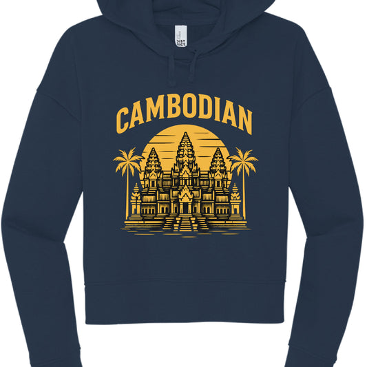 The image shows a navy blue, cropped hoodie featuring a yellow graphic design on the front.

Design and Garment Details
Text: The word "CAMBODIAN" is printed in a bold, arched, yellow serif font at the top of the design.

Illustration: A yellow graphic of Angkor Wat is centered below the text. The temple is depicted against a large, circular sunset background with horizontal lines. Two palm trees frame the temple on either side.

Hoodie Style:

Fit: It is a cropped hoodie with a relaxed, dropped-shoulder sl