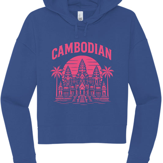 This image shows a cobalt blue, cropped pullover hoodie featuring a pink graphic design that highlights Cambodian heritage.

Design Details
Typography: The word "CAMBODIAN" is printed in an arched, bold sans-serif font across the top of the graphic.

Illustration: A detailed, pink silhouette of the Angkor Wat temple is the central focus.

Background Elements: * A large, solid pink circle (representing a sun) sits behind the temple towers.

Two palm trees frame the temple on either side.

Horizontal lines at