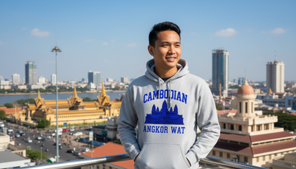 Person wearing a hoodie with 'Cambodian Angkor Wat' text, standing in front of a cityscape with buildings and a river.