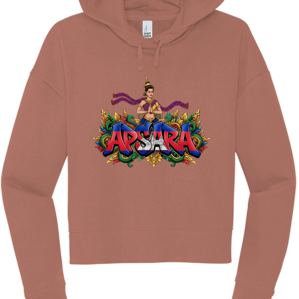 This image shows a terracotta or dusty rose-colored cropped hoodie with a vibrant, illustrative graphic on the chest.

Graphic Design Features
The Text: The word "APSARA" is written in large, bold, block letters. The letters are filled with the colors and imagery of the Cambodian flag, featuring red and blue horizontal bands and the silhouette of Angkor Wat in the center.

The Figure: Above the text is an illustration of an Apsara dancer, a traditional Khmer celestial being. She is depicted in 