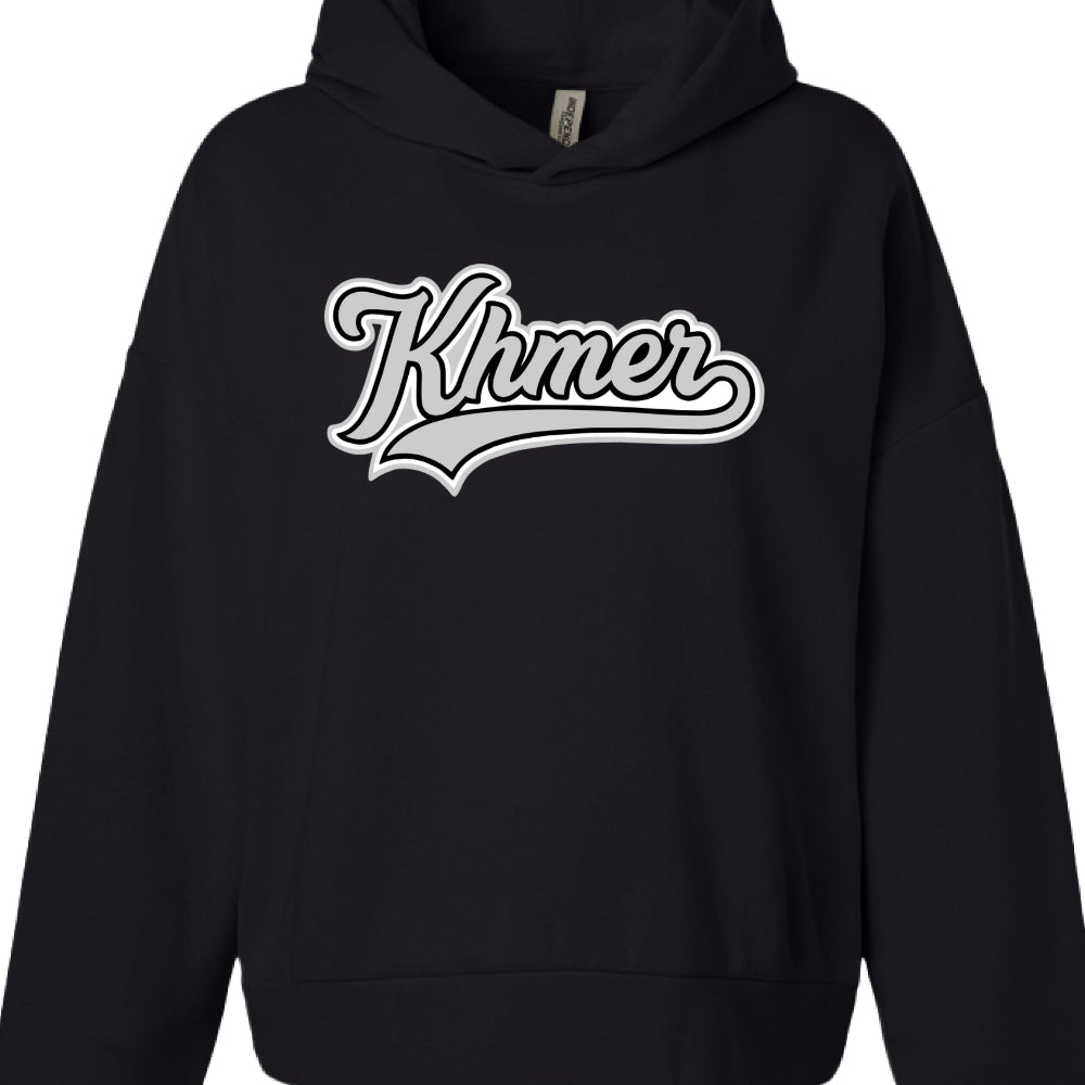 Text: The word "Khmer" is written in a stylized, cursive script.

Typography Style: The font mimics a classic baseball or varsity aesthetic, characterized by thick outlines and a "swoosh" or tail extending from the final letter "r" back under the word.

Color Palette: The graphic uses a monochrome scheme consisting of white, light gray, and black to create a layered, 3D effect.

Garment Features:

Color: Deep black.

Fit: It appears to be a standard or slightly oversized fit with dropped shoulders.

Label: 