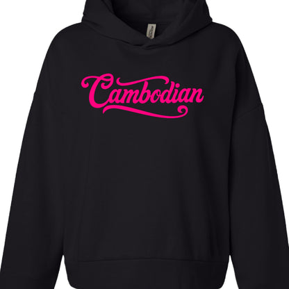 Text: The word "Cambodian" is printed across the center of the chest.

Font: A stylized, cursive script with thick strokes and decorative flourishes, similar to a retro baseball or "varsity" logotype.

Color: A vibrant, electric pink.

Detail: A thick blue underline (swoosh) extends from the final "n" back toward the beginning of the word, characteristic of classic sports apparel designs.