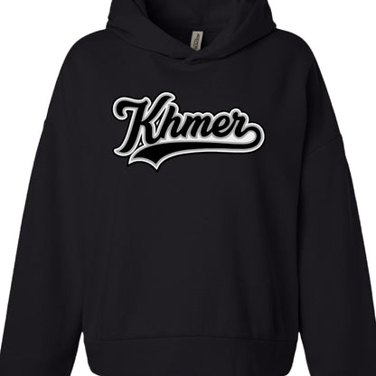 Text: The word "Khmer" is printed in the center of the chest.

Font & Style: The text uses a stylized, cursive script with thick outlines, reminiscent of vintage baseball or varsity lettering.

Color Palette: The design is monochromatic, featuring white text with heavy black and grey shadowing to create a three-dimensional, layered effect.

Design Element: A thick, black-and-grey-contoured "swoosh" or underline extends from the bottom of the word toward the left.