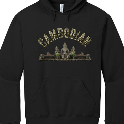 The Text: The word "CAMBODIAN" is written in an arched, block-letter font. Each letter is textured with images of the serene, carved stone faces found at the Bayon Temple.

The Central Image: Positioned directly below the text is a detailed, realistic depiction of Angkor Wat, the famous temple complex. It features the characteristic five towers and lush greenery surrounding the base.

The Hoodie: The garment is a standard black hoodie with a front "kangaroo" pocket, drawstring hood, and a visible "Jerzees" 