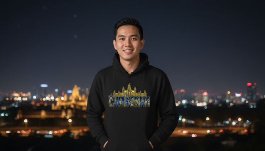 Person wearing a black hoodie with a colorful design in front of a city skyline at night.