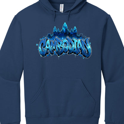 The central graphic utilizes a monochromatic blue color scheme with white accents to create depth and contrast:

Typography: The word "CAMBODIAN" is written in a large, bubbly graffiti font. The letters feature a blue camouflage or water-like pattern, highlighted with white outlines to make them pop against the dark fabric.

Iconography: Silhouetted behind the text is the unmistakable outline of Angkor Wat, the famous Cambodian temple complex. The towers are rendered in various shades of blue, blending the 