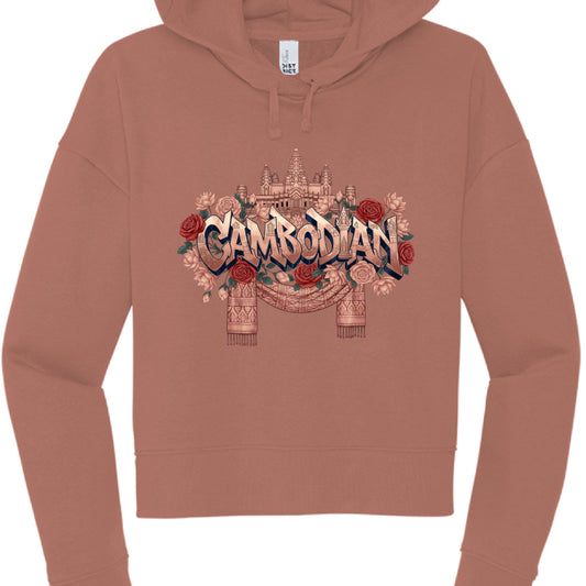 Terracotta Heritage Hoodie
The second image features a terracotta or dusty rose cropped hoodie with a design that emphasizes traditional architecture and florals.

Typography: The word "CAMBODIAN" is written in a sharp, 3D block font with a bronze metallic finish.

Architectural Detail: A detailed, monochrome illustration of Angkor Wat sits directly above the text.

Floral and Fabric Elements:

The text is surrounded by a lush arrangement of red and peach roses.

Draped beneath the central graphic is a trad