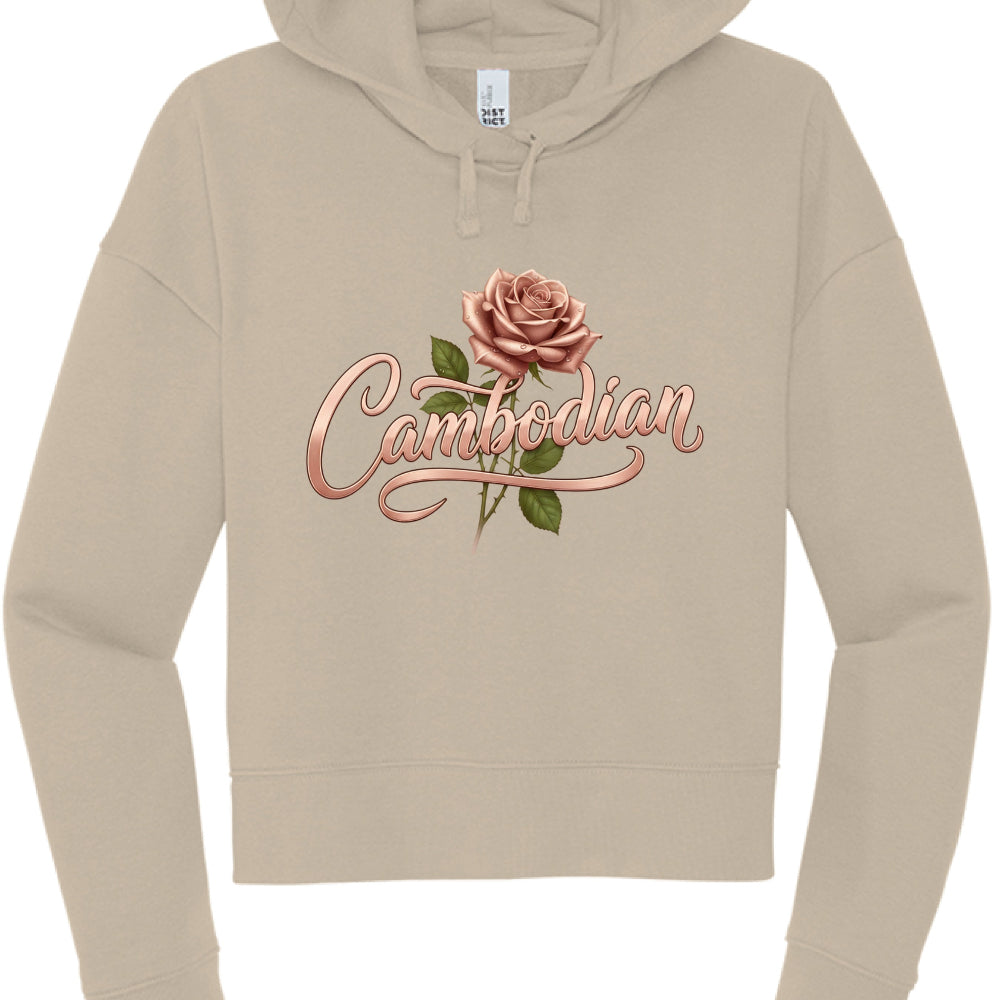 This image features a tan or beige cropped hoodie with a custom graphic design centered on the chest. The overall aesthetic is soft, feminine, and elegant.

Design Details
Typography: The word "Cambodian" is written in a stylized, rose-gold cursive font. The lettering has a metallic, 3D sheen with soft highlights and shadows, giving it a ribbon-like appearance.

Floral Element: A realistic, dusty rose (matching the color of the text) is positioned just above the "m" and "b" in the text. It includes green le