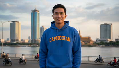 Person wearing a blue hoodie with 'CAMBODIAN' text, standing in front of city skyline and river.