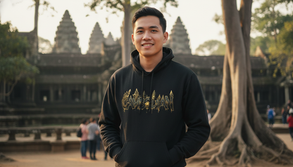 Man wearing a black hoodie with gold design in front of Angkor Wat.