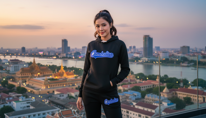 Woman wearing a black hoodie with 'Cambodian' text, standing in front of a cityscape.