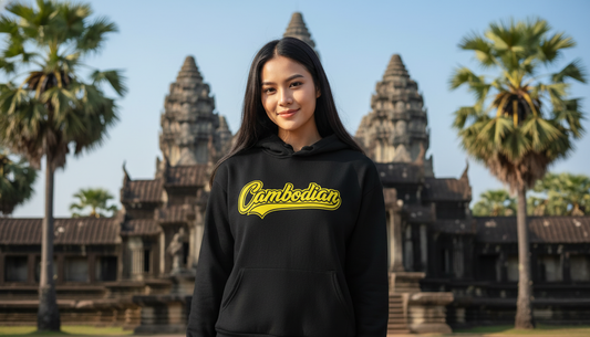 Person wearing a black hoodie with 'Cambodian' text in yellow, standing in front of Angkor Wat.