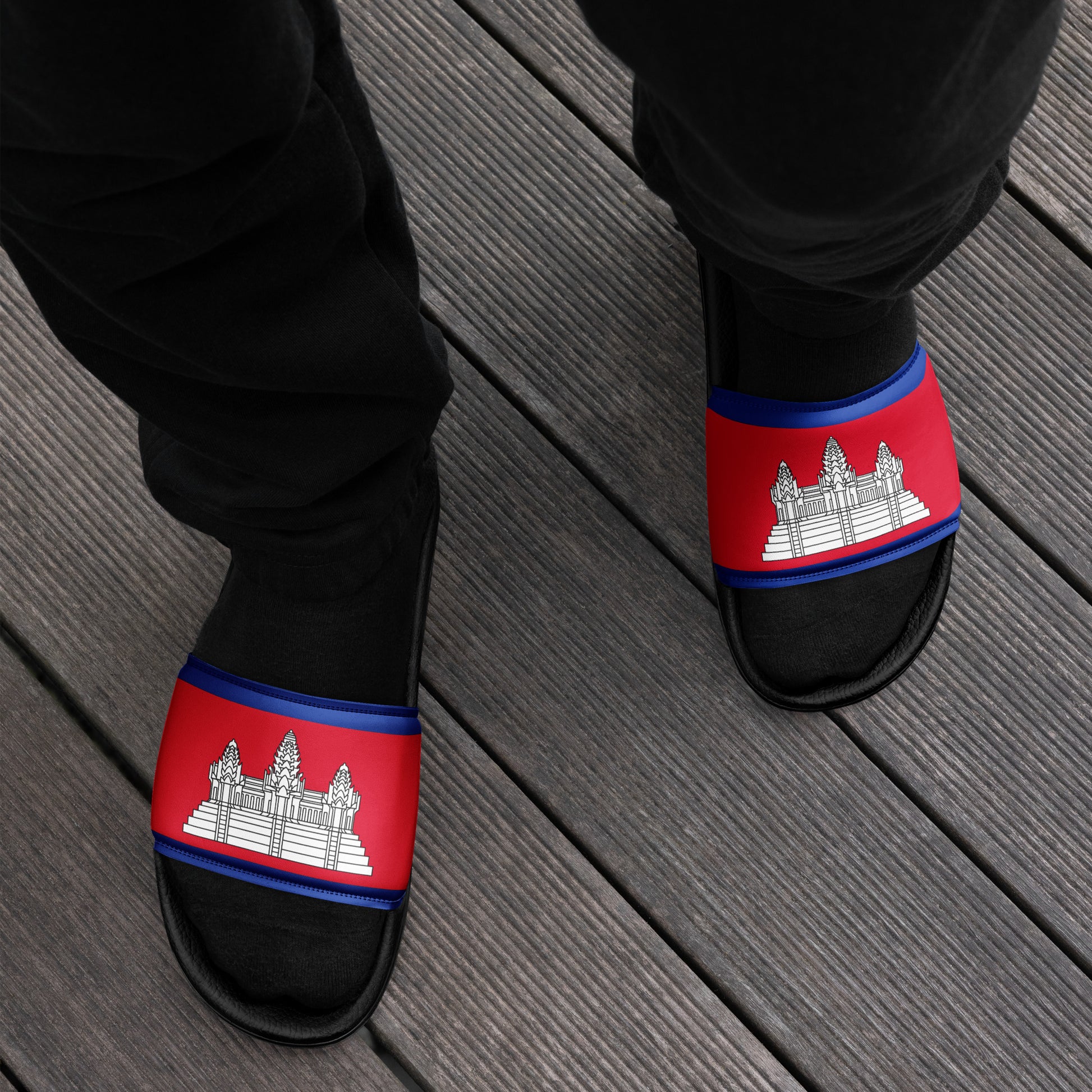 Black slippers with red and blue bands featuring a temple design on a wooden floor.