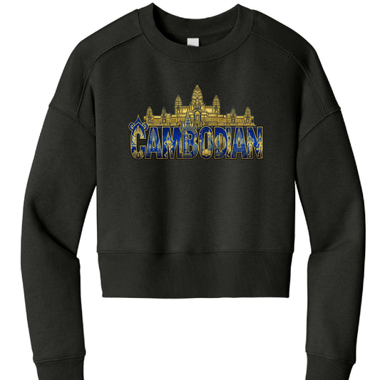 The image shows a black cropped sweatshirt with an ornate graphic design centered on the chest.

Garment Details
Type: Long-sleeved crewneck sweatshirt with a cropped fit.

Color: Solid black.

Construction: Features drop-shoulder sleeves, ribbed cuffs, and a thick ribbed hem at the waist.

Graphic Design
The artwork uses a regal gold and blue color palette and includes several cultural elements:

Top Layer: A gold silhouette of the Angkor Wat temple complex sits above the text.

Typography: The word "CAMBO