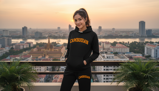 Person wearing a black hoodie with 'CAMBODIAN' text, standing on a rooftop with a cityscape view.