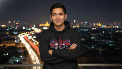 Person wearing a black hoodie with colorful design in front of a cityscape at night.