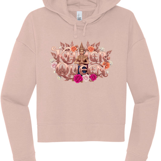This image features a dusty rose or blush-colored cropped hoodie showcasing a highly detailed, ornate graphic centered on the chest. The design celebrates Cambodian heritage with a royal and floral theme.

Design Elements
Typography: The words "KHMER QUEEN" are displayed in a bold, metallic rose-gold font with intricate, carved-style detailing. The letter "Q" in "Queen" features a silhouette of the Angkor Wat temple towers within its center.

Central Figure: A woman dressed in traditional Cambodian Apsara a