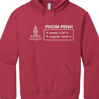 The graphic is a minimalist, white line-art layout that includes the following elements:

Illustration: On the left, there is a detailed architectural line drawing of the Independence Monument (Vimean Ekareach) located in Phnom Penh.

Main Text: To the right of the illustration, the city name "PHOM PENH" is printed in a bold, sans-serif font. (Note: There appears to be a minor spelling error on the garment, omitting the "N" in Phnom).

Coordinates Box: Below the city name, a rectangular box contains geograp