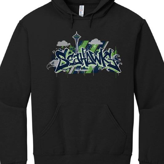 The image shows a black pullover hoodie featuring a vibrant, stylized graphic centered on the chest. The design is a tribute to the Seattle Seahawks NFL team, blending sports culture with a gritty, urban aesthetic.

Design Breakdown
Typography: The word "SEAHAWKS" is written in large, aggressive graffiti-style "wildstyle" lettering. It uses a color palette of navy blue, action green, and white outlines to match the team's official colors.

Iconography:

Space Needle: A silhouette of Seattle’s most iconic la