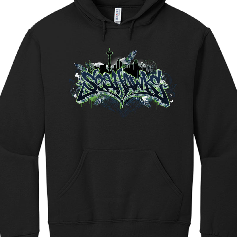 This image features a black pullover hoodie with a complex, multi-layered graphic celebrating the Seattle Seahawks.

Graphic Elements
Central Text: The word "SEAHAWKS" is displayed in a jagged, graffiti-style 3D font using navy blue, action green, and white outlines.

Seattle Skyline: Above the text is a black silhouette of the Seattle skyline, featuring recognizable structures like the Space Needle and the Great Wheel.

Accents: The design is adorned with several stylized feathers in blue and green, which 