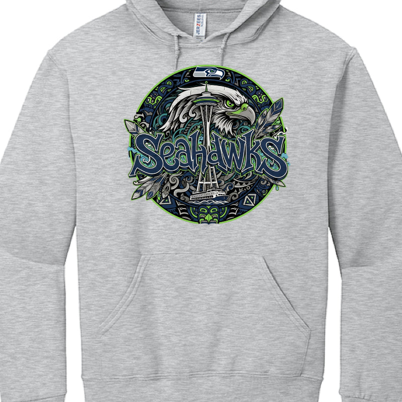 The provided images show two different hoodies featuring stylized graphics for the Seattle Seahawks.

Black Hoodie Graphic (image_a4655b.jpg)
This design uses a sharp, urban aesthetic:

Typography: The word "SEAHAWKS" is rendered in a jagged, 3D graffiti-style font with blue, green, and white outlines.

Skyline: A black silhouette of the Seattle skyline, including the Space Needle and the Great Wheel, sits directly above the text.

Decorative Accents: The design includes several stylized feathers in blue an