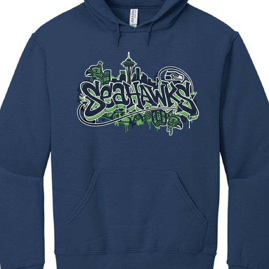 This image shows a navy blue hooded sweatshirt featuring a detailed, stylized graphic for the Seattle Seahawks.

Apparel Details
Garment: A pullover hoodie made of a 50/50 cotton/polyester blend, specifically a Jerzees brand product.

Design Style: The graphic utilizes an urban "street art" or graffiti aesthetic, characterized by bold, jagged lettering and neon green paint splatter effects.

Graphic Composition
The central artwork combines several Pacific Northwest and team-specific motifs:

Typography: The