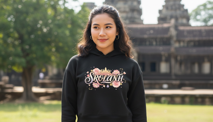 Woman wearing a black hoodie with floral design and text in front of a historical building.
