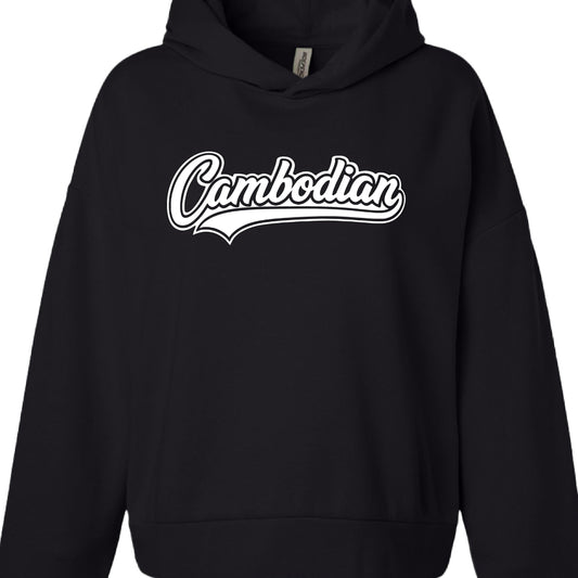 Color: Solid black.

Garment Style: It appears to be a heavy-weight or oversized hoodie, featuring dropped shoulders and a front kangaroo pocket. A small white manufacturer's tag is visible inside the collar.

Graphic Design:

Text: The word "Cambodian" is printed in the center.

Typography: The font is a white, retro-style cursive script with a thick black outline.

Accents: A stylized "swoosh" or underline extends from the bottom of the letter "n," giving it a classic athletic or "varsity" aesthetic.